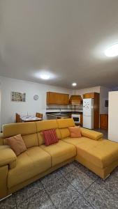 a living room with a yellow couch and a kitchen at Casa Tranquila in Ingenio