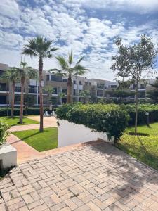 a brick walkway with palm trees and a building at Appart familial avec terrasse et piscine, à 2 pas de la plage des nations - Rabat in Sidi Bouqnadel