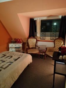 a bedroom with a bed and chairs and a window at De Oude Bakkerij in Onderdendam +17 photos