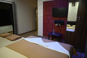 ein Hotelzimmer mit einem Bett und einem Flachbildfernseher in der Unterkunft Coral Beach Resort, Diveagar in Diveagar