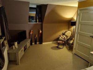 a bedroom with a room with a tv and a chair at De Oude Bakkerij in Onderdendam