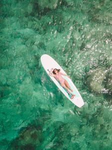 a woman on a surfboard in the water at Dhoani Maldives Boutique in Kendhoo