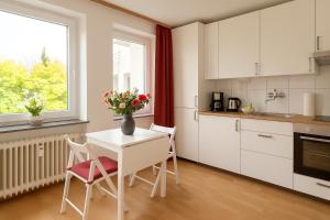 a kitchen with a table and chairs and a vase with flowers at Quiet & Modern Studio near Tram & River Lech in Augsburg