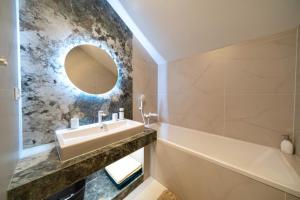 een badkamer met een wastafel, een bad en een spiegel bij Villa Merry in Vysoké Tatry +69 foto's