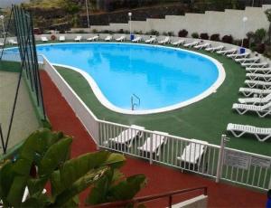 una grande piscina con sedie a sdraio bianche accanto ad essa di Peace Rooftop Tenerife a Tabaiba