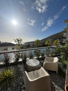 a patio with two white chairs and a pool at Mira apartman Oliva Residence in Petrovac na Moru