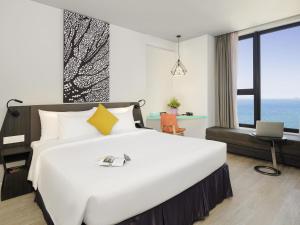 a bedroom with a large white bed and a desk at ibis Styles Nha Trang in Nha Trang