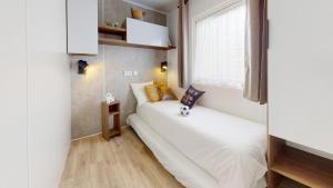 niewielka sypialnia z białym łóżkiem i oknem w obiekcie MH263 3 chambres et 2 salles de bain dans camping 4 étoiles w mieście Saint-Julien-en-Born +16 zdjęć