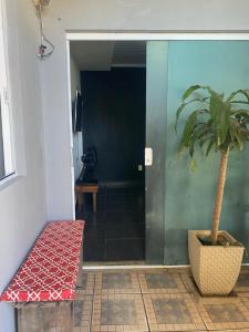 uma planta em vaso ao lado de uma porta com um banco em Casa completa em cabo frio em Cabo Frio