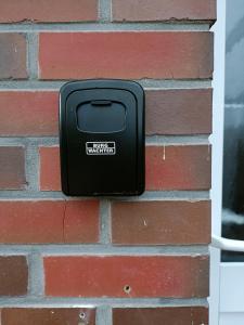 a black mailbox on the side of a brick wall at Apartment an der Fehnroute in Leer