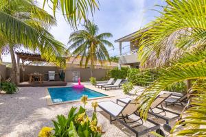 a backyard with a pool and chairs and a house at Oasis Boutique Resort - Magnesium zwembad in Willemstad