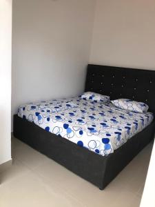 a bed with a black frame and blue and white comforter at Apartamento 1 Quarto - Baixa de Luanda in Luanda