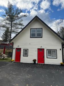 una casa blanca con dos puertas rojas en Modern Home &Cozy, en Lake Placid