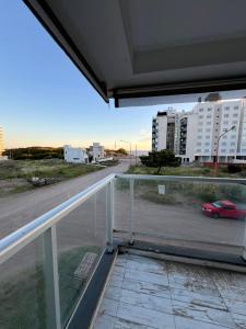 einen Blick aus dem Fenster einer Straße mit einem roten Auto in der Unterkunft Semipiso de Categoria con Vista al Mar in Monte Hermoso