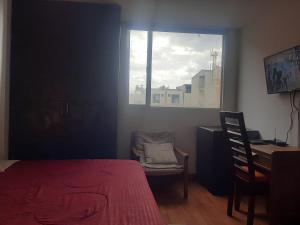 a bedroom with a red bed and a chair and a window at Acevedo Inn Cerca a la embajada Americana , Corferias, G 12, U Nacional, Movistar Arena , Claro Eventos, a 30 minutos del Aeropuerto, Cerca al Can y a la Clinica Meredy contacto trescientosdoscautroseistrescerosieteochoseis in Bogotá