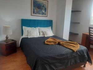 a bed with a blue headboard in a room at Acevedo Inn Cerca a la embajada Americana , Corferias, G 12, U Nacional, Movistar Arena , Claro Eventos, a 30 minutos del Aeropuerto, Cerca al Can y a la Clinica Meredy contacto trescientosdoscautroseistrescerosieteochoseis in Bogotá