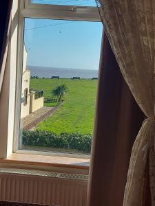 a window with a view of a green field at Coastline cottage Pakefield, 2 minutes walk to the beach in Pakefield