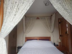 ein Bett mit weißen Vorhängen in einem Schlafzimmer in der Unterkunft Coastline cottage in Pakefield