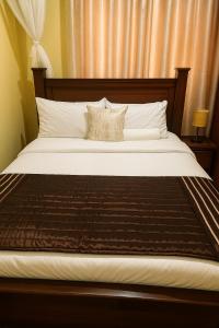 a bedroom with a large bed with a wooden headboard at Bonaventure Apartment A in Kisumu