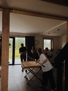 a group of people standing around a ping pong table at Brīvdienu māja & pirts meža vidū - Saraiķu Sanderi in Saraiķi