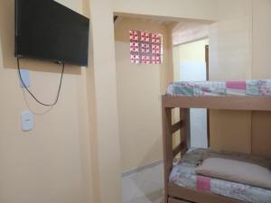 a room with two bunk beds and a flat screen tv at Kitnet confortável no centro de cabo frio in Cabo Frio