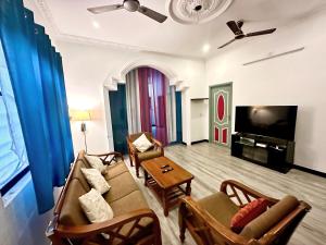 a living room with a couch and chairs and a tv at KPS homestay in Pondicherry