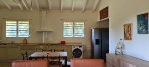 une cuisine avec une table, des chaises et un réfrigérateur dans l'établissement Chambre d'hotes "Villa Rayon Vert", à Deshaies