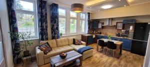 Una sala de estar con un sofá y una cocina. en Niebieski apartament pod Borową Górą, en Jedlina-Zdrój