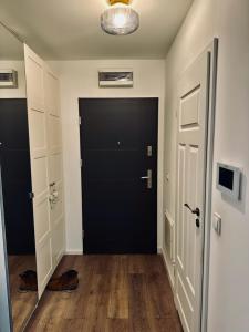 un couloir vide avec une porte noire et du parquet dans l'établissement Apartament Suwałki Szpitalna, 