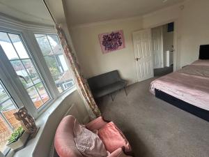 a bedroom with a bed and two chairs and a window at Eastcote 1st Floor Retreat 2 Bedroom Suite with Kitchen and Bathroom 2mins to Tube 20mins to Heathrow and Wembley 25mins Drive to Harry Potter World FREE PARKING in Eastcote