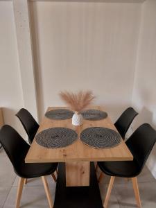 ein Holztisch mit schwarzen Stühlen drumherum und einem Mittelstück in der Unterkunft Appartement cosy et calme in Saint-Pierre-de-Boeuf