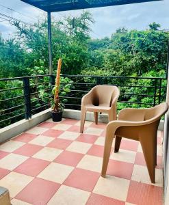 a balcony with two chairs sitting on a checkered floor at Villa Sereno Belgaum in Belgaum