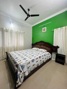 a bedroom with a bed with a green wall at Villa Sereno Belgaum in Belgaum