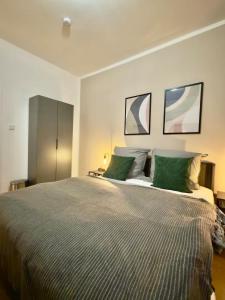 Stylish City Apartment mit Beamer & Balkon Zentral في هاغين: غرفة نوم بسرير كبير مع وسائد خضراء