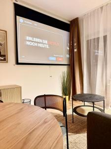Stylish City Apartment mit Beamer & Balkon Zentral في هاغين: شاشة عرض في غرفة بها كرسيين وطاولة
