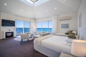 a white bedroom with a large bed and a fireplace at Saltwater - Absolute Oceanfront, Fire Pits, some Villas with Hot Tubs and Sauna in Falmouth