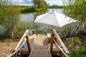 a wooden dock with an umbrella on a river at Wonderland in Henfield +7 photos