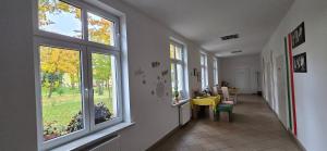 a hallway with windows and a yellow table and chairs at Strefa Zen pokoje z klimatem przy parku. in Jelenia Góra