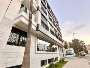 a white building with a palm tree in front of it at Spacious, Quiet Apartment with Parking , Fiber in Casablanca