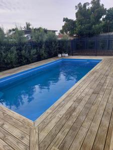 een blauw zwembad met een houten terras bij Inner city Sanctuary in Gisborne