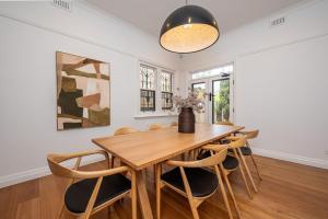 een eetkamer met een houten tafel en stoelen bij Poolside at Kindrogan - St Kilda in Melbourne