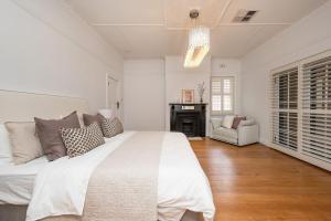 een witte slaapkamer met een groot bed en een open haard bij Poolside at Kindrogan - St Kilda in Melbourne +23 foto's