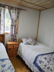 a bedroom with two beds and a window at Hospedaje y Cabañas Ensenada Puerto Varas in Puerto Varas
