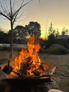 a fire is burning in a campfire in a field at Entre Las Sierras Tiny House Solo Adultos Cabañas in Villa Giardino