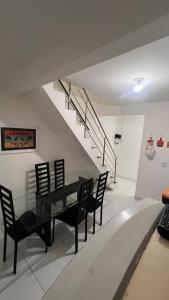 a dining room with a black table and chairs and stairs at Conj Pajuçara 3 minutos da praia, 5 pessoas! in Maceió