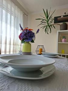 a table with plates and a vase with purple flowers at Ferienhaus Ninua, 2 Schlafzimmer, Garten Terrasse in Hemmingstedt