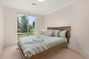 a bedroom with a large bed with a window at Bay Breeze Cottage in Callala Bay