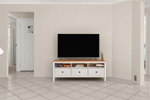 a television on a white entertainment center in a living room at Bay Breeze Cottage in Callala Bay