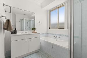 a white bathroom with a tub and a sink at Bay Breeze Cottage in Callala Bay +10 photos