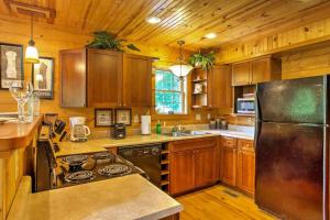 eine Küche mit Holzschränken und einem Edelstahlkühlschrank in der Unterkunft Hot Tub & WiFi - ManeStay - Red River Gorge KY in Slade